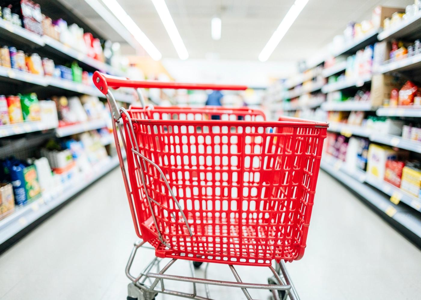 A red shopping cart in a bright store aisle